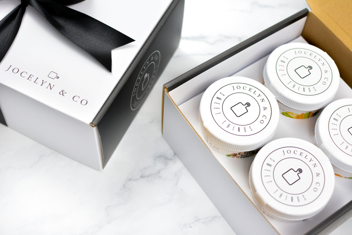 Jocelyn & Co. Fruit & Nuts Gift Box with four white-lidded jars beside its ribbon-tied lid
