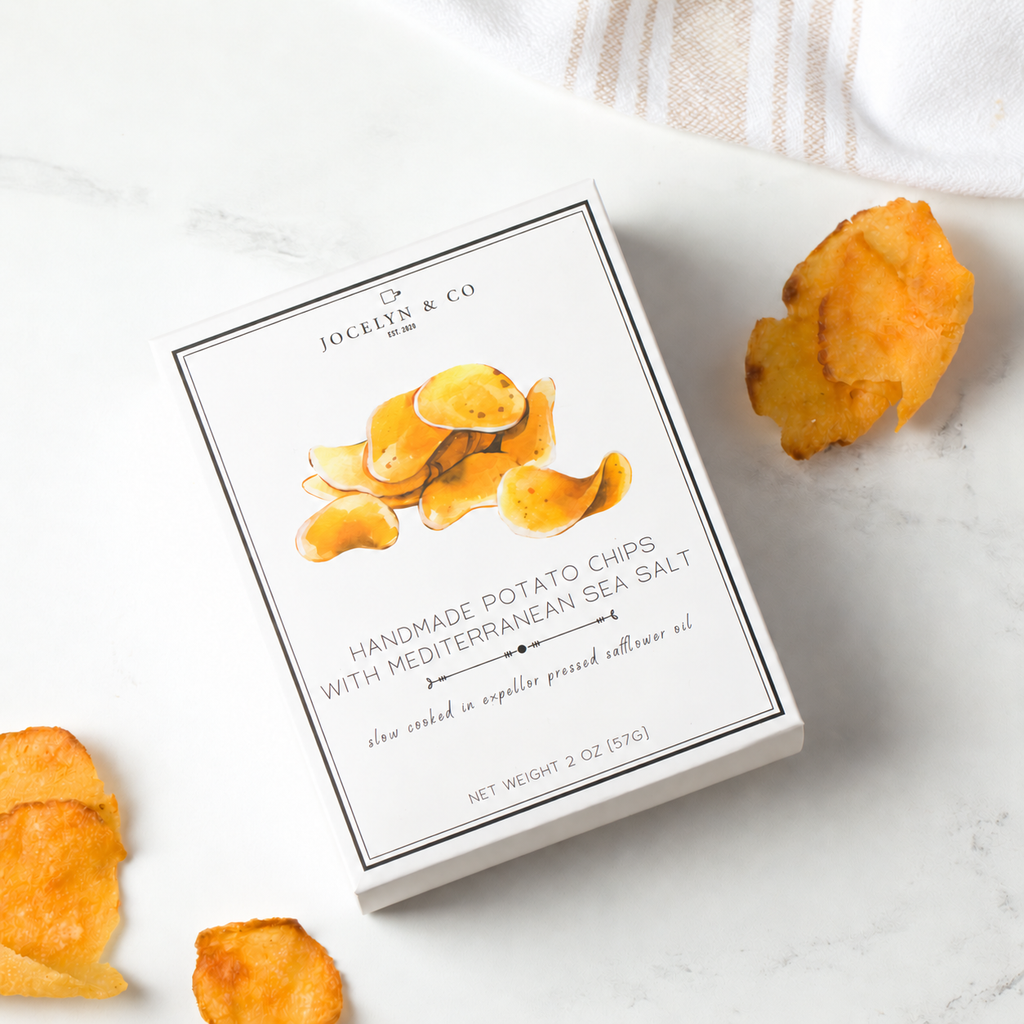 Jocelyn & Co. Handmade Potato Chips with Mediterranean sea salt, beside golden potato chips on a pale countertop