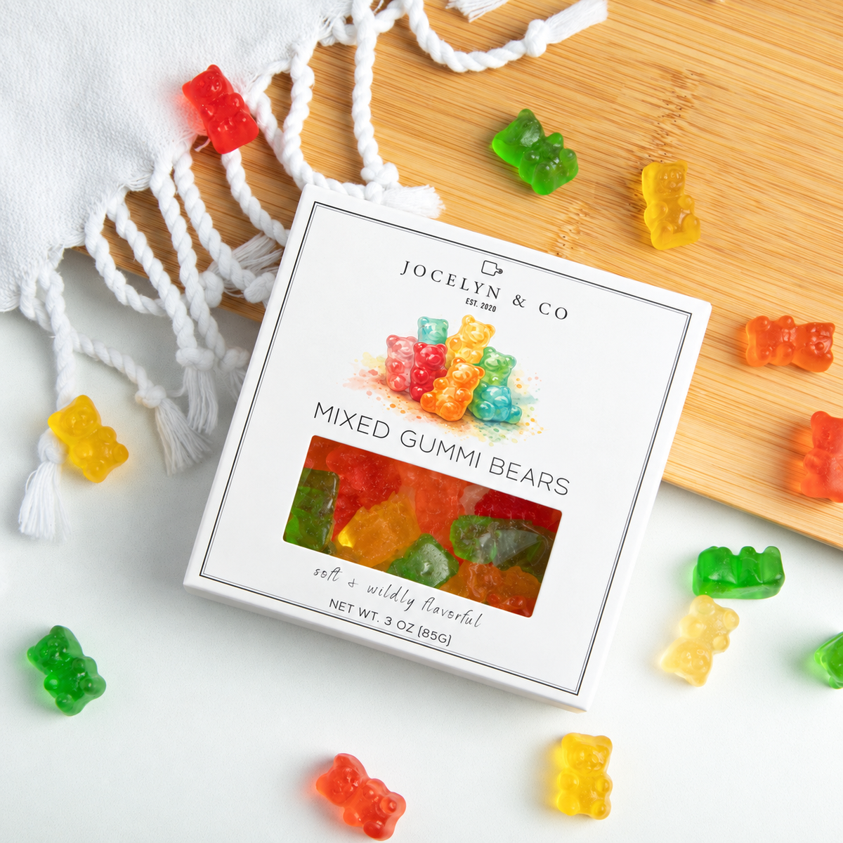Jocelyn & Co. Mixed Gummi Bears 3 oz square box with watercolor bear artwork and a clear candy window, styled with loose gummi bears on a bamboo board and pale countertop