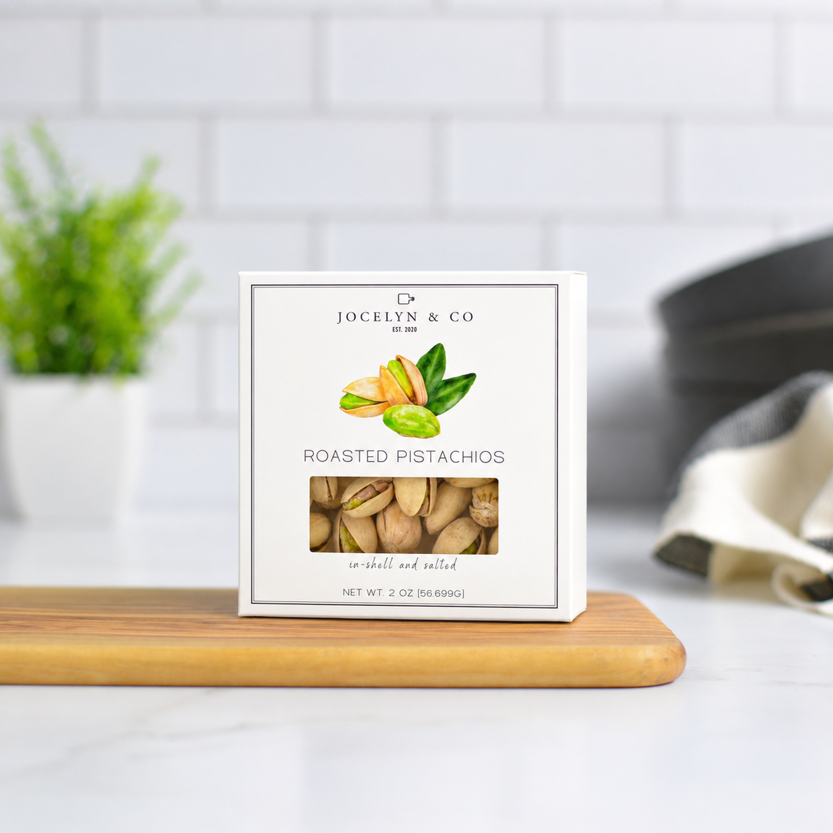 Jocelyn & Co. Roasted Pistachios, upright on a wooden board in a softly lit kitchen setting